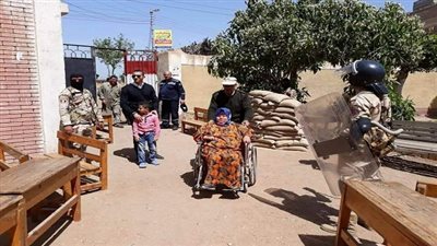 مساعدة سيدة من ذوي الاحتياجات الخاصة أثناء الإدلاء بصوتها بمدرسة بكفر شكر